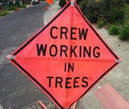 Construction sign reading crews working in trees