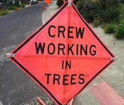 Construction sign reading crews working in trees