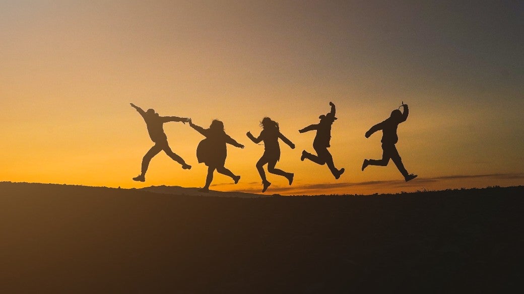 Silhouette of happy family or friends jumping in the sunset