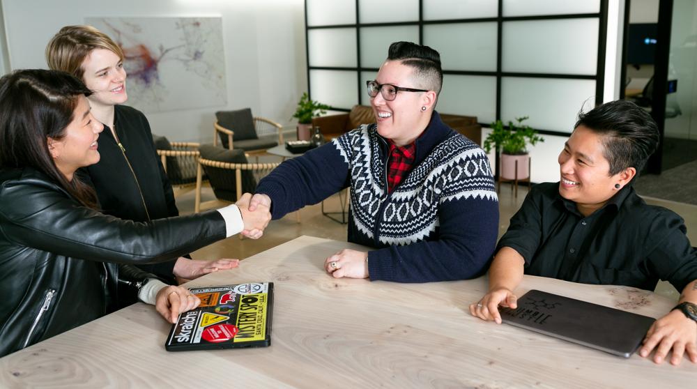 Teammates shaking hands and smiling in an office