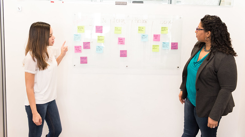 two women kanban brainstorming and brainmapping with post-it notes on a whiteboard 