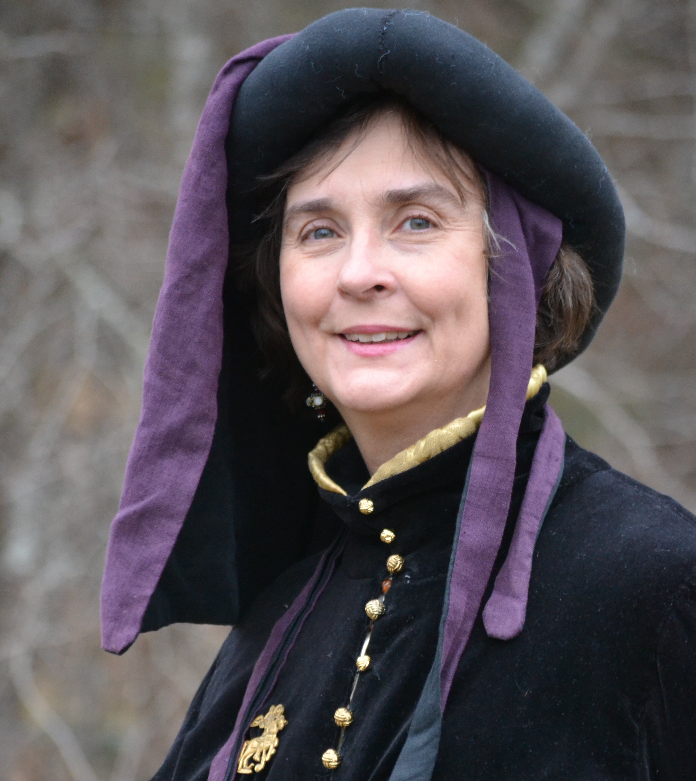 Headshot of Ingrid Towey wearing a chaperone hat and houppelande