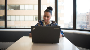 Business woman on laptop sitting in front of window
