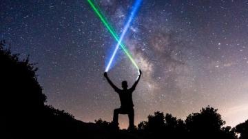 Man with lasers in night sky