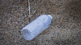 Empty plastic water bottle on sand pollution trash