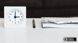 Clock, pen, and notepad on a desk
