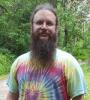 Tie dye wearing hippie Matthew with a long beard hiking in the woods.
