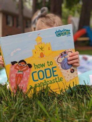 Young girl reading How to Code a Sandcastle