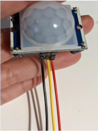 Photo of a hand holding the sensor with black, red, and yellow cables